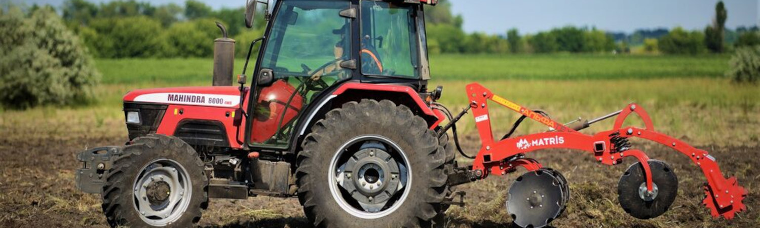 A Mahindra tractor hauling a tiller for harvesting.